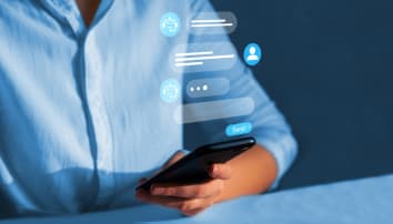 Women in a blue blouse communicates with a chatbot on her phone.