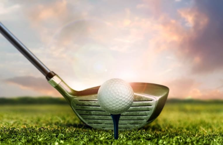 Golf club and ball on grass with under sunset sky lights