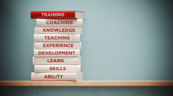 Books of training, development and skills are sitting on top of each other. The books have unique texts on their spines related to training subject.