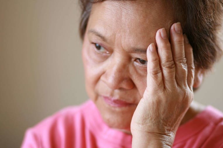 elderly asian women holding hand to head