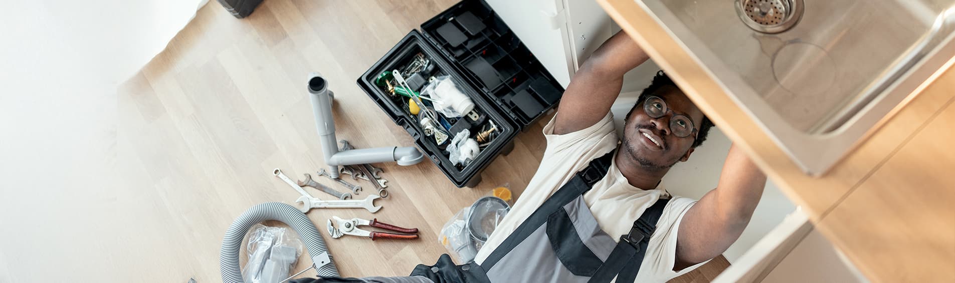 Plumber working on pipes under sink